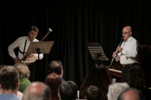 Due musicisti che suonano strumenti a fiato durante un concerto con il pubblico in vista.